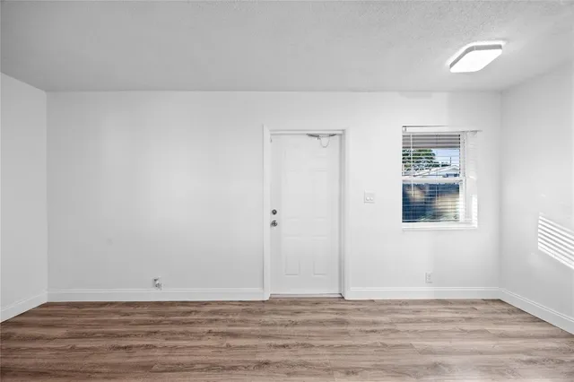 a view of an empty room with wooden floor and a window