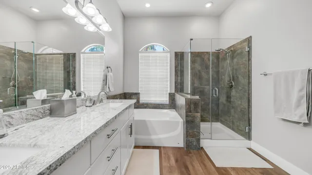 a spacious bathroom with a granite countertop sink a mirror a shower and a bathtub