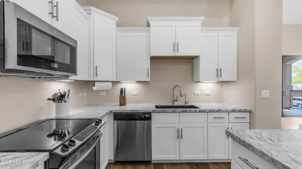 a kitchen with stainless steel appliances granite countertop a stove a sink and a microwave