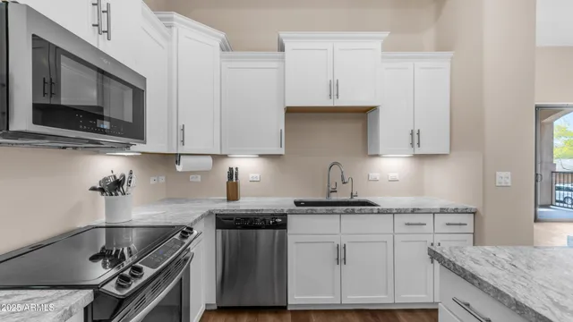 a kitchen with stainless steel appliances granite countertop a stove a sink and a microwave