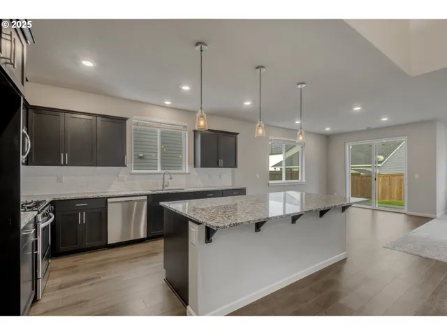 a kitchen with stainless steel appliances granite countertop a sink dishwasher a stove and a oven with wooden floor