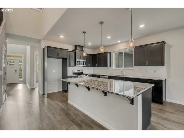 a kitchen with stainless steel appliances granite countertop a sink a stove and a wooden floors