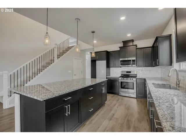 a kitchen with stainless steel appliances kitchen island granite countertop a sink refrigerator and cabinets