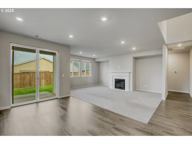 a view of a livingroom with wooden floor a fireplace and window