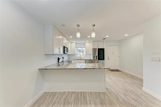 a large white kitchen with a sink and dishwasher with wooden floor