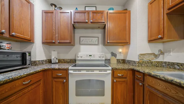 a kitchen with granite countertop a sink stove and cabinets