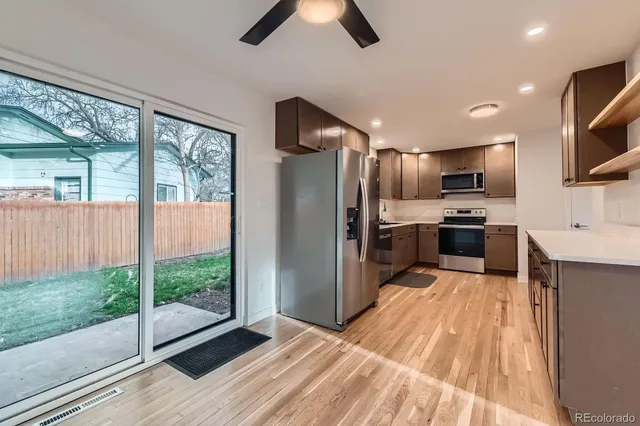 a kitchen with stainless steel appliances kitchen island granite countertop a refrigerator oven a sink dishwasher and a view of living room