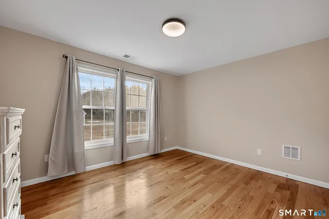 a bathroom with a toilet a double vanity sink and a mirror