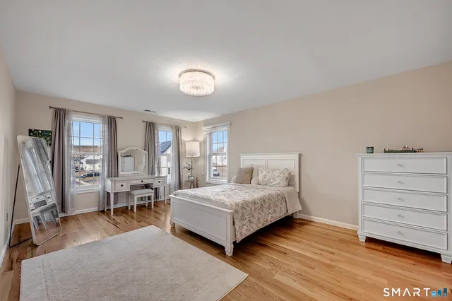 a view of a hallway to a livingroom with wooden floor and stairs