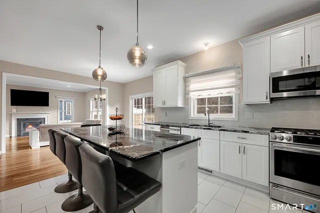 a kitchen with stainless steel appliances granite countertop a stove a sink a microwave oven a stove and a dining table with wooden floor