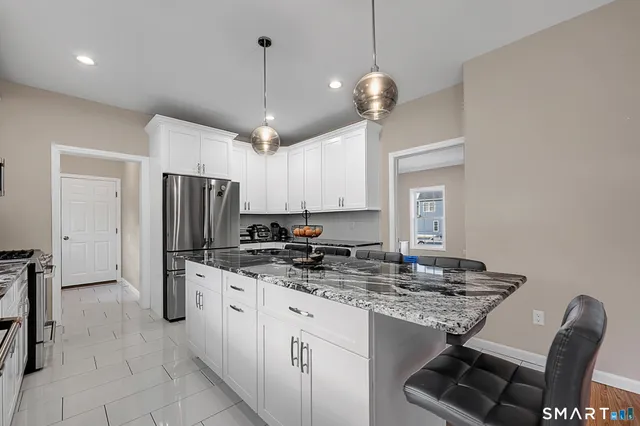 a kitchen with stainless steel appliances granite countertop a sink a stove a refrigerator and island