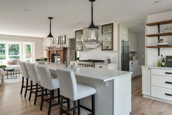 a kitchen with stainless steel appliances kitchen island granite countertop a table chairs and white cabinets