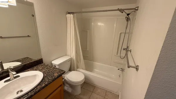 a bathroom with a granite countertop bathtub shower sink vanity and toilet