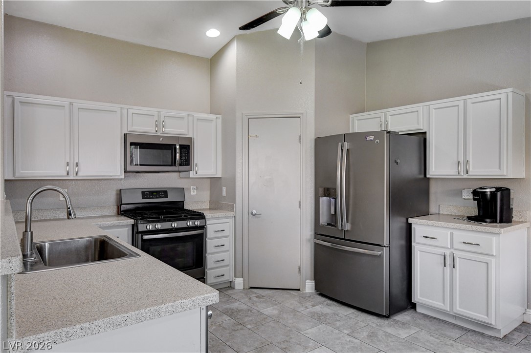 910 Cobblestone Cove Road North Las Vegas, NV 89081 - Photo 10 of 30 Culinary space featuring bright white cabinetry and essential stainless-steel appliances.