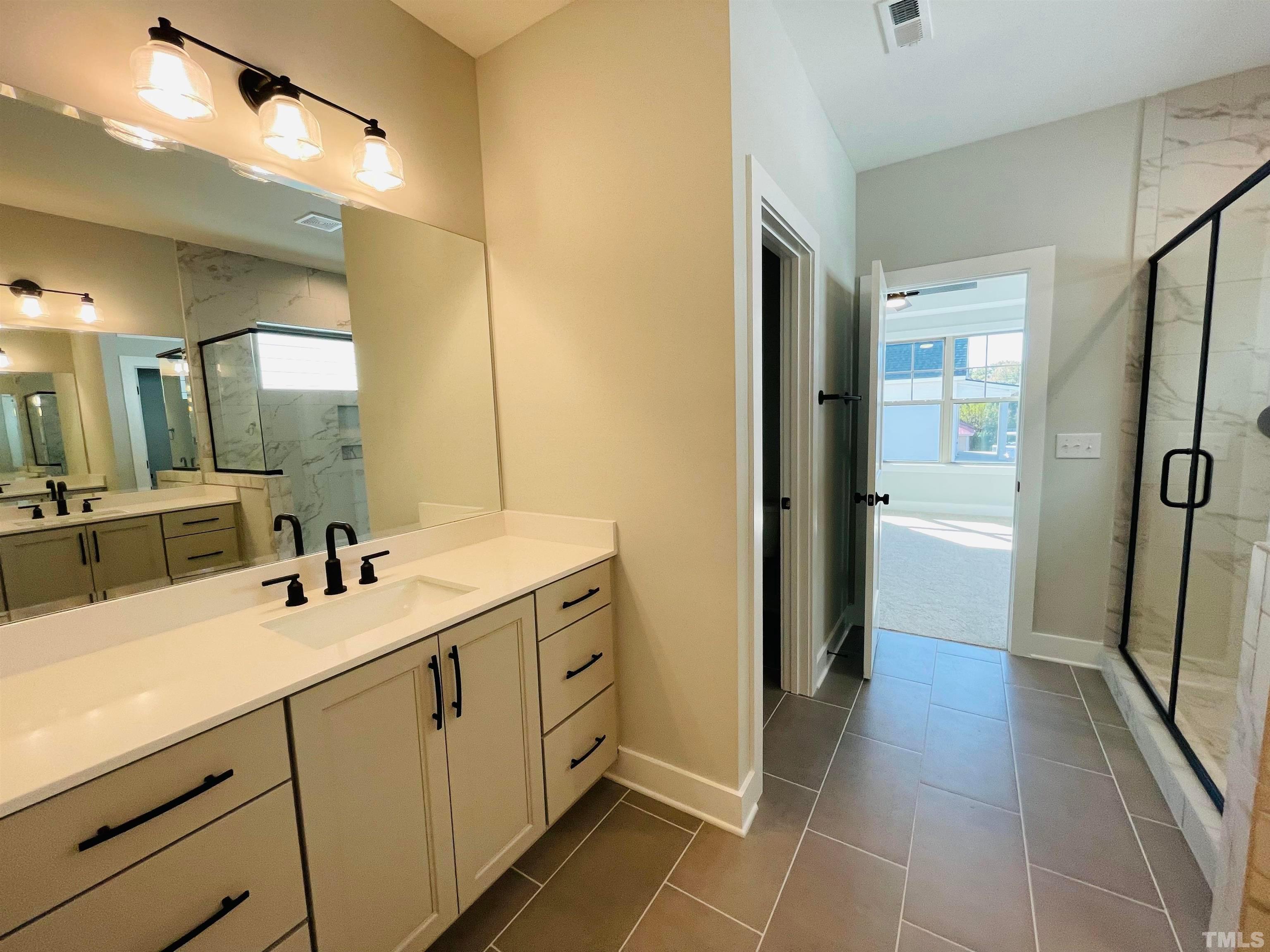 200 East Moore Street Apex, NC 27502 - Photo 17 of 32 a bathroom with a double vanity sink a mirror and a shower