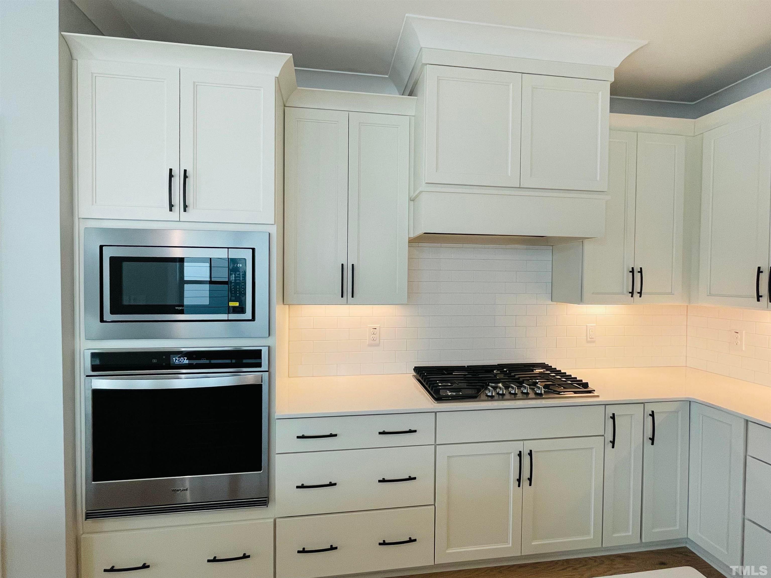 200 East Moore Street Apex, NC 27502 - Photo 6 of 32 a kitchen with granite countertop white cabinets and stainless steel appliances