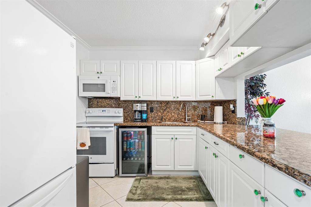 a kitchen with granite countertop a sink stainless steel appliances and white cabinets
