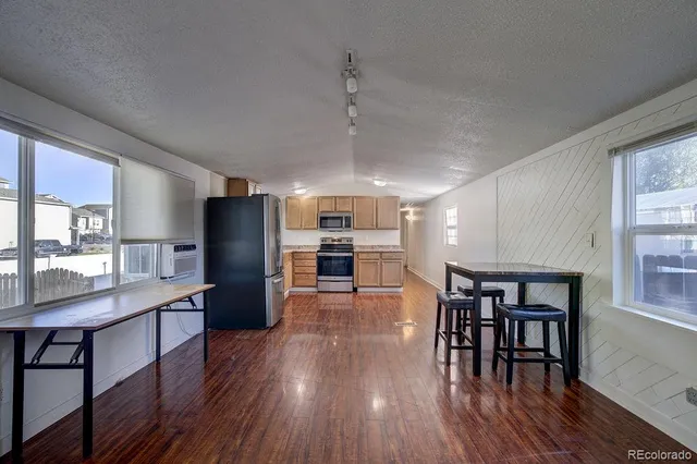 a kitchen with stainless steel appliances wooden floor dining table and chairs