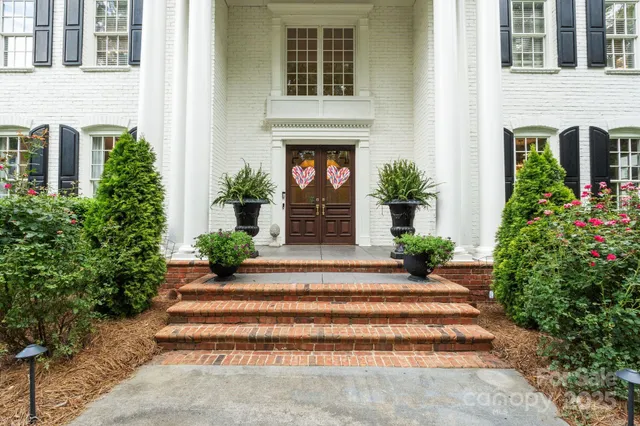 a view of a house with potted plants and a fountain