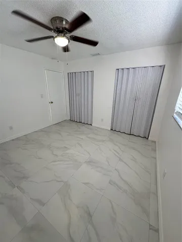an empty room with a ceiling fan and a window