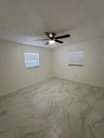 an empty room with a ceiling fan and window