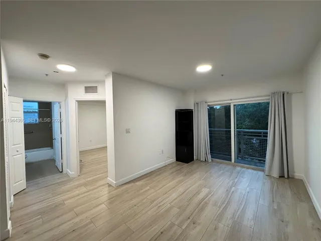 an empty room with wooden floor & windows and closet