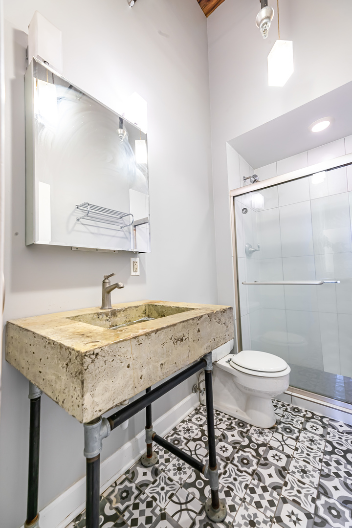 312 North May Street, Unit 5F Chicago, IL 60607 - Photo 14 of 16 a bathroom with a granite countertop sink toilet a mirror and shower