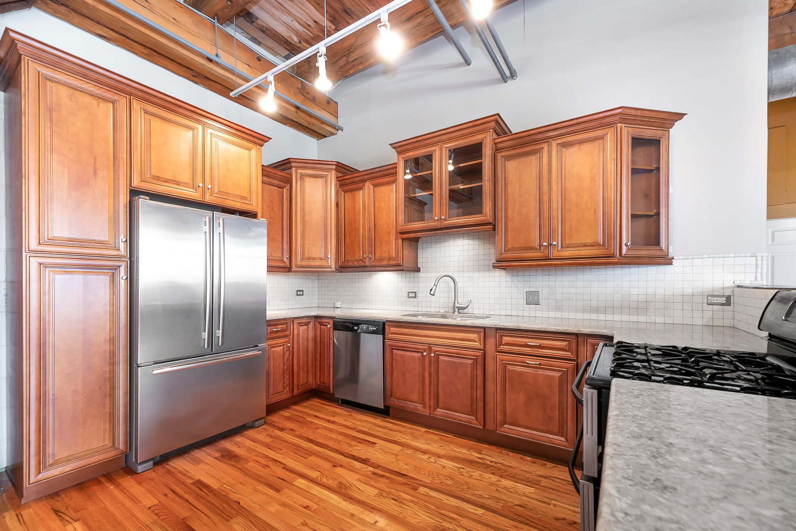 312 North May Street, Unit 5F Chicago, IL 60607 - Photo 7 of 16 a kitchen with stainless steel appliances granite countertop a refrigerator and wooden cabinets