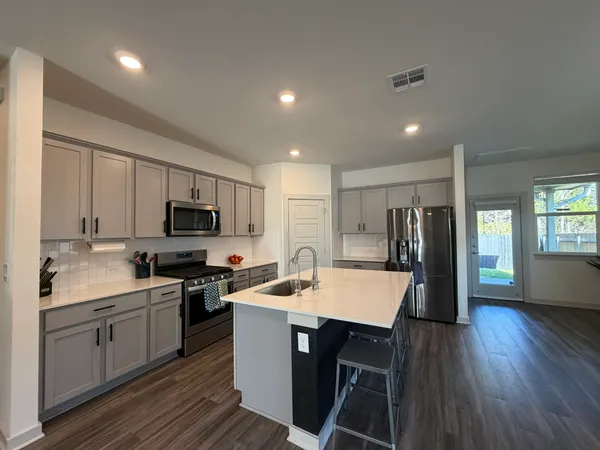 a kitchen with appliances a sink a counter top space and a center island