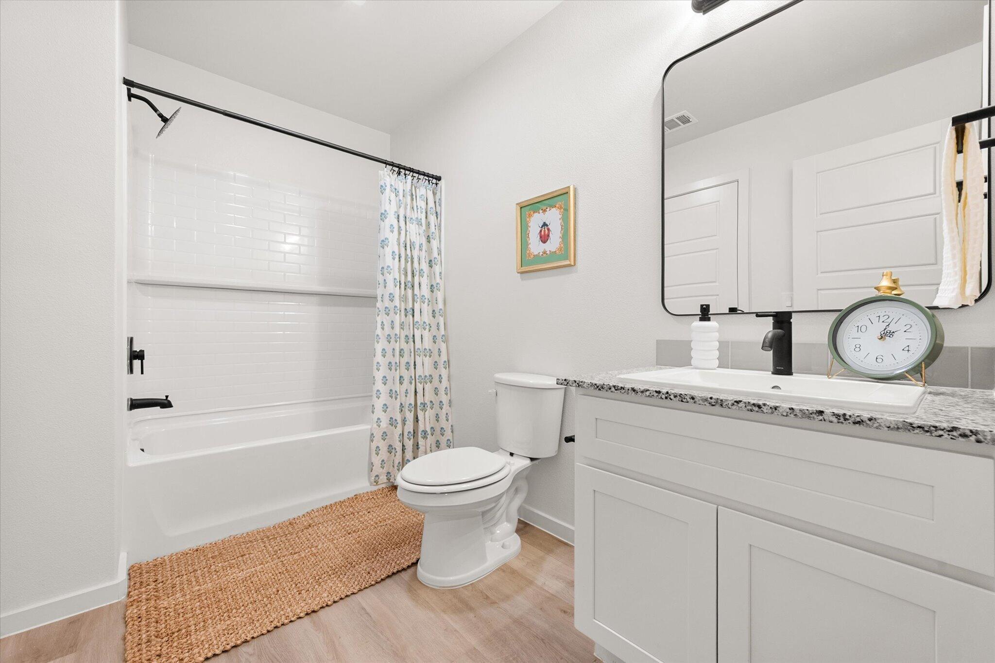 5506 Smith Street Lubbock, TX 79416 - Photo 13 of 16 a bathroom with a granite countertop sink toilet a mirror and shower