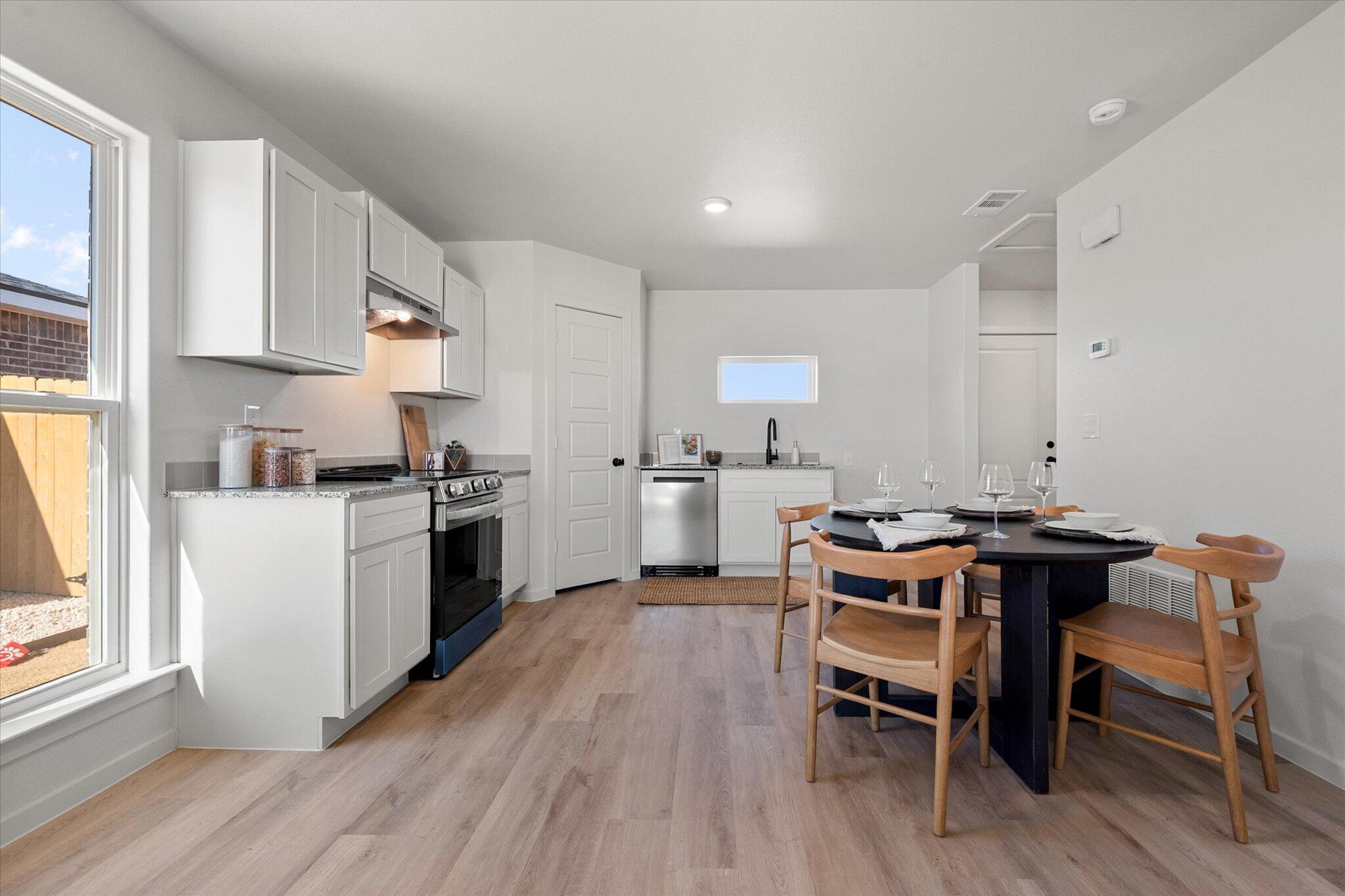 5506 Smith Street Lubbock, TX 79416 - Photo 7 of 16 a kitchen with a table chairs a sink dishwasher stove and cabinets with wooden floor