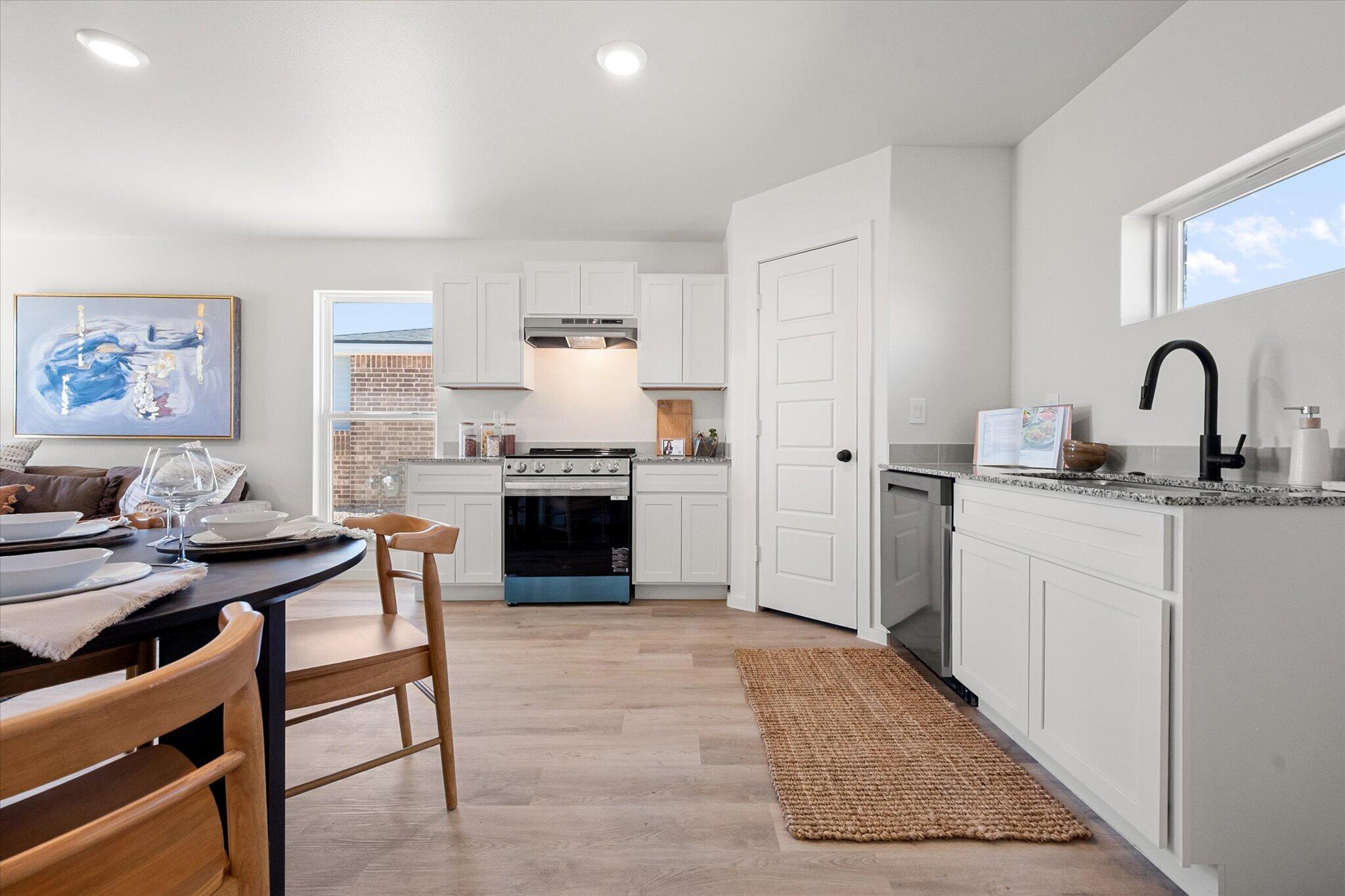 5506 Smith Street Lubbock, TX 79416 - Photo 9 of 16 a kitchen with stainless steel appliances granite countertop a stove a sink dishwasher and a refrigerator with wooden floor