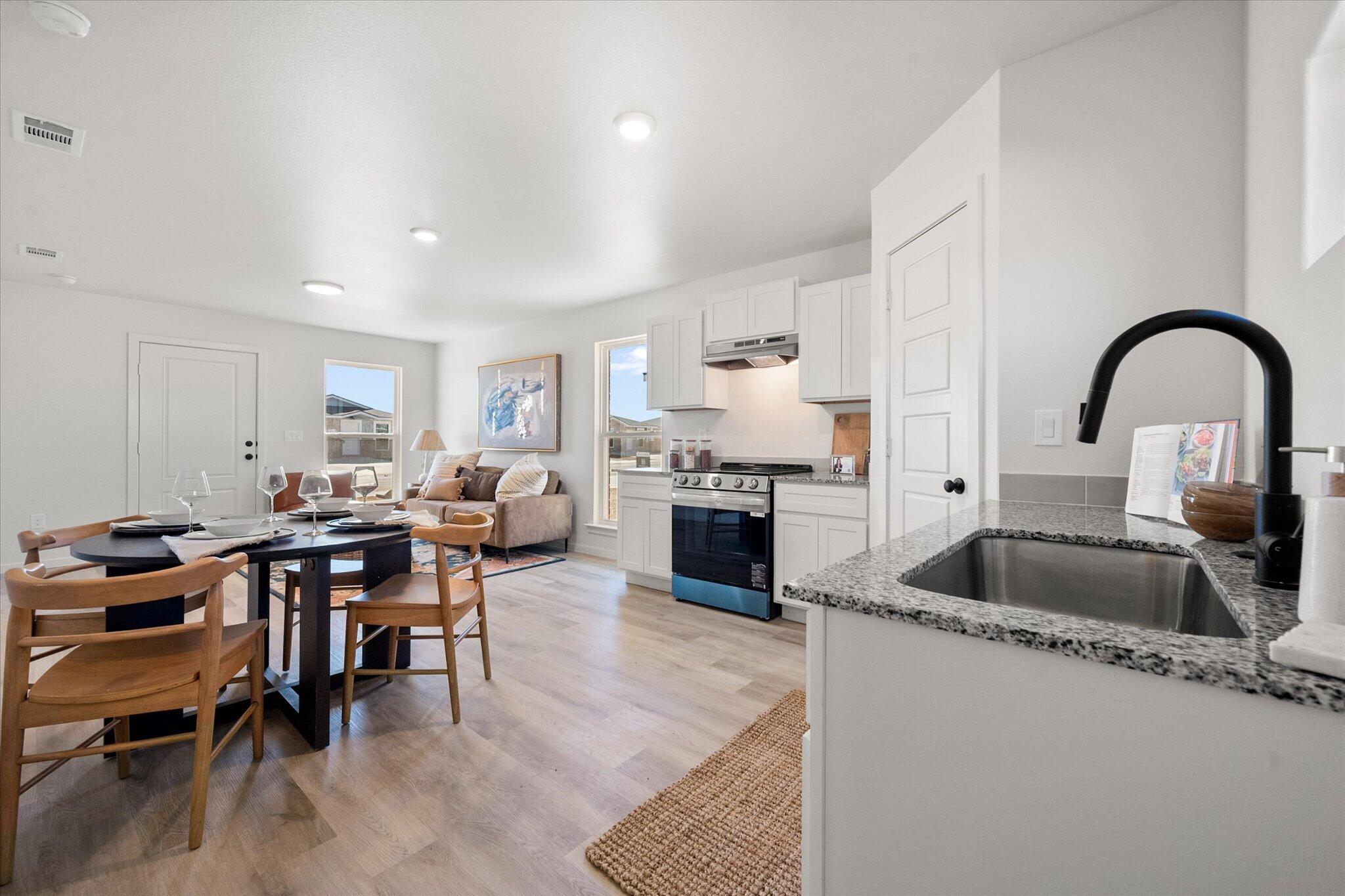 5506 Smith Street Lubbock, TX 79416 - Photo 10 of 16 a kitchen with sink stove and white cabinets with wooden floor