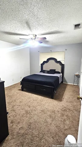 a bedroom with a bed and a lamp on dresser