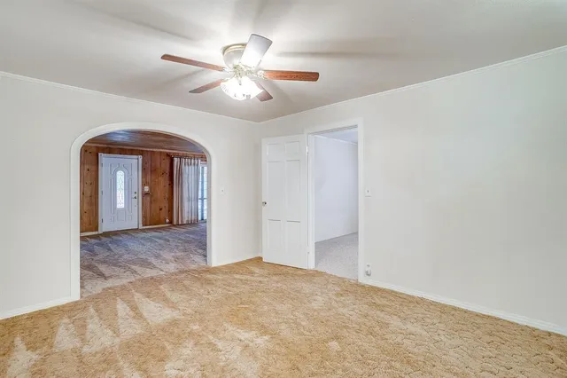 a view of an empty room with chandelier fan