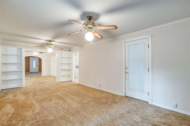 an empty room with windows and ceiling fan