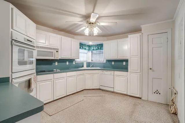 a kitchen with granite countertop white cabinets and white stainless steel appliances