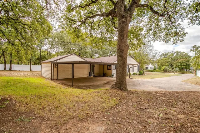 a view of a house with a yard and large tree