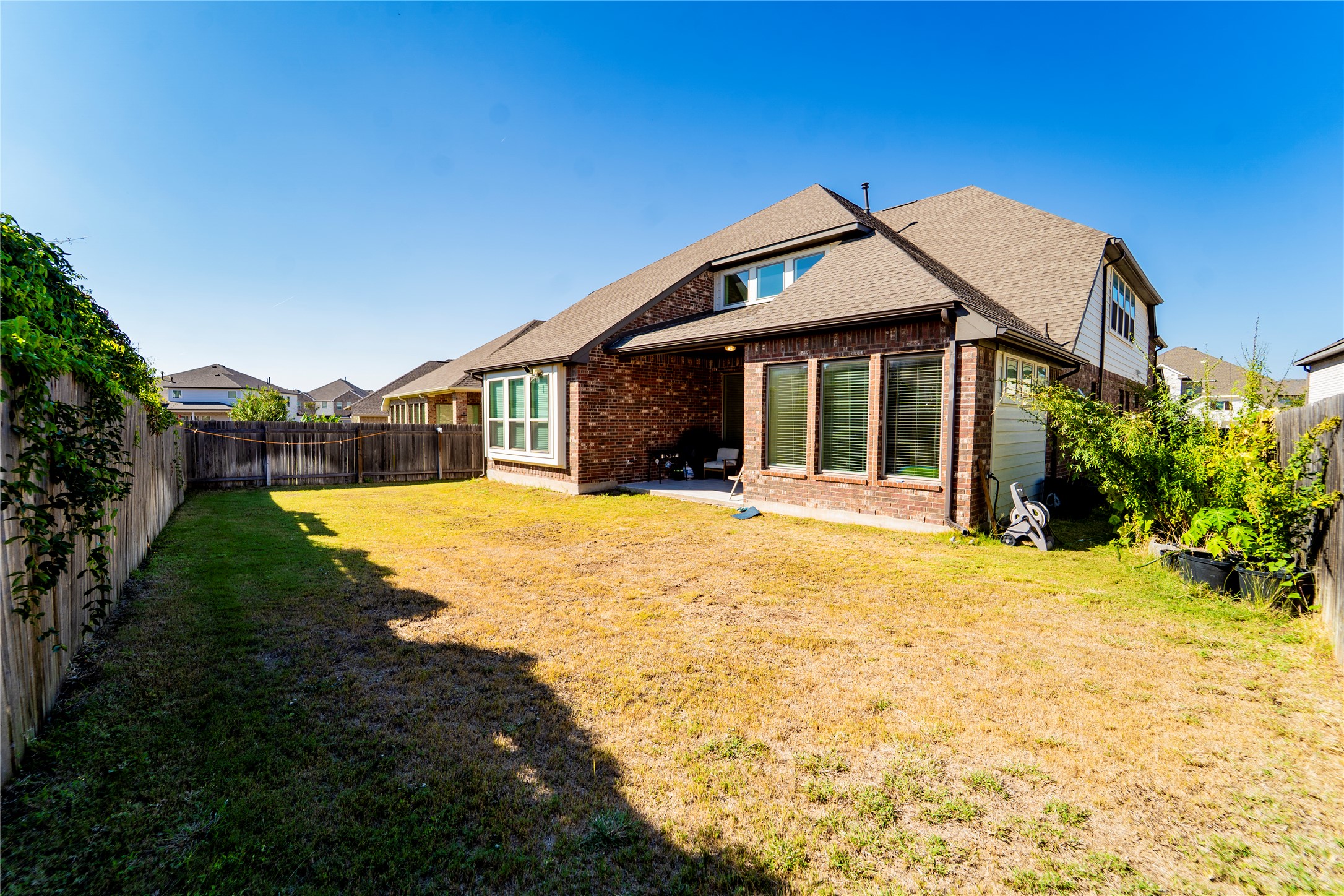 20813 Carries Ranch Road Pflugerville, TX 78660 - Photo 28 of 29 Back of property with brick siding, a fenced backyard, a patio, and roof with shingles