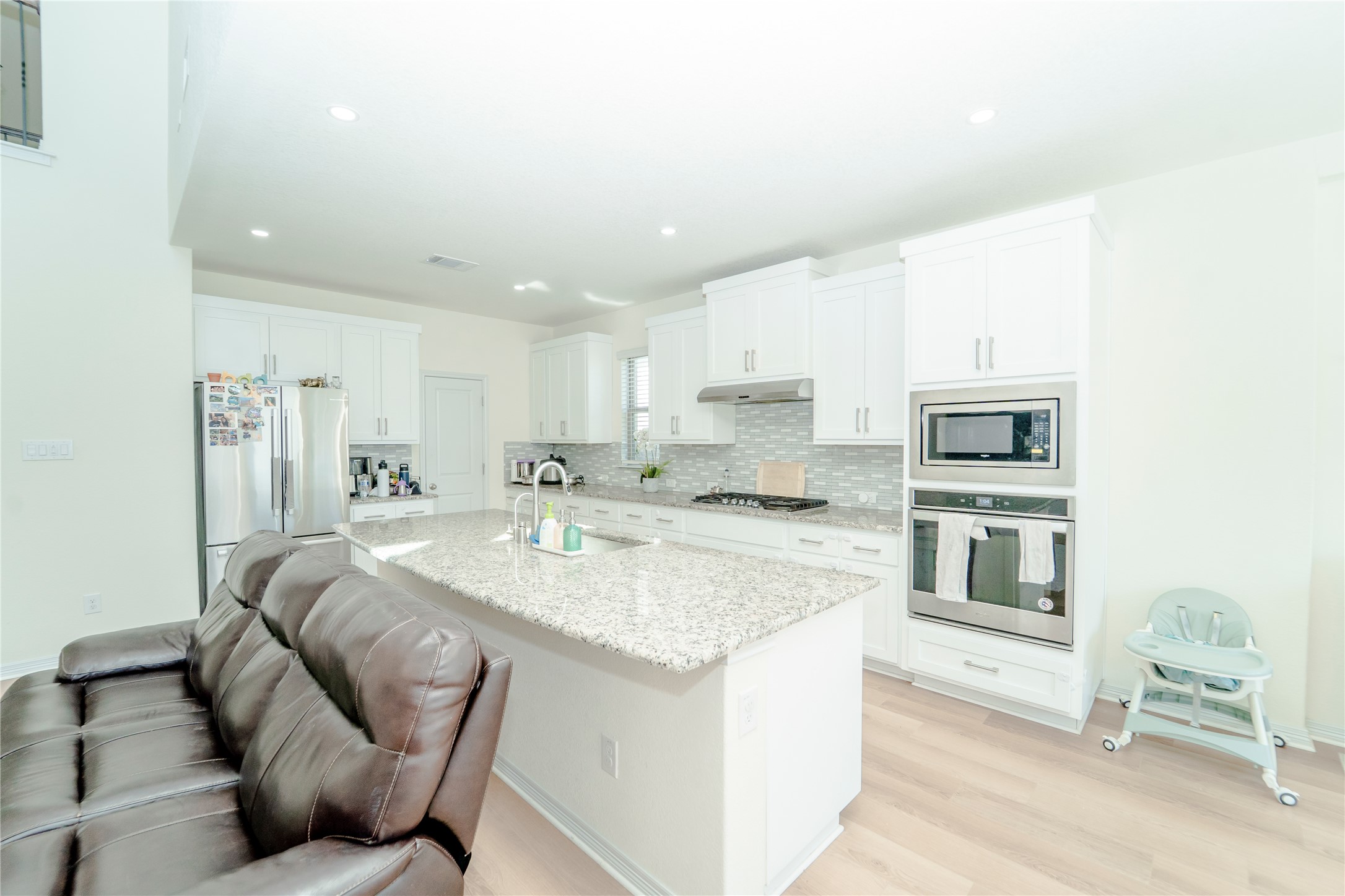 20813 Carries Ranch Road Pflugerville, TX 78660 - Photo 8 of 29 Kitchen with white cabinetry, stainless steel appliances, light stone countertops, light wood-style flooring, and recessed lighting