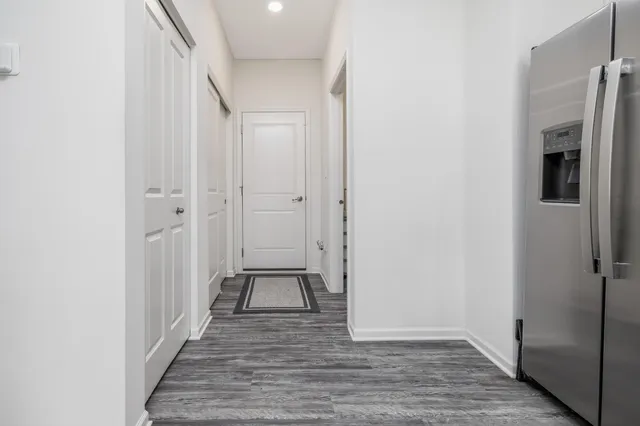 a view of a hallway with wooden floor and a bathroom