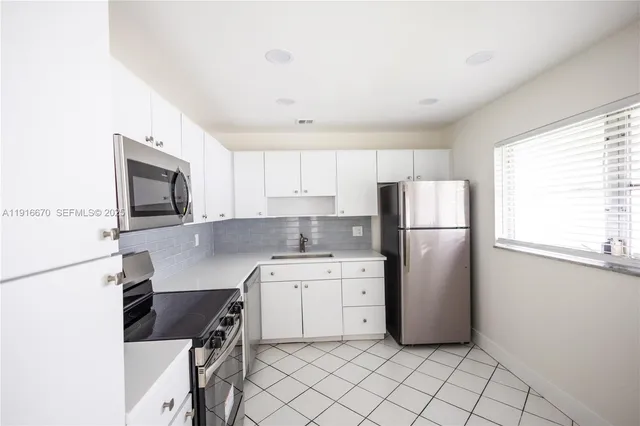 a kitchen with a refrigerator a stove top oven a sink and cabinets