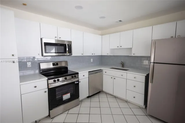a kitchen with white cabinets appliances and sink