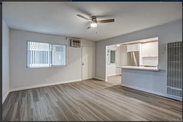 a view of an empty room with a window and wooden floor