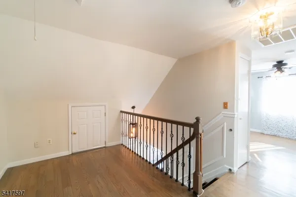 a view of a hallway with a dining table & a chandelier fan