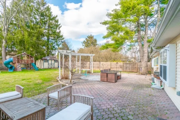 a view of a backyard with couches plants and large trees