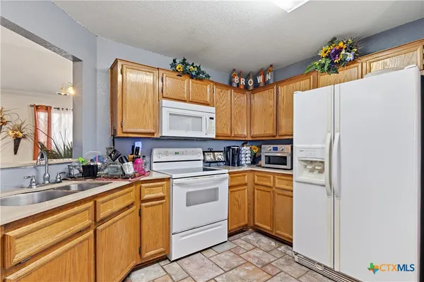 a kitchen with a refrigerator a sink cabinets and wooden floor