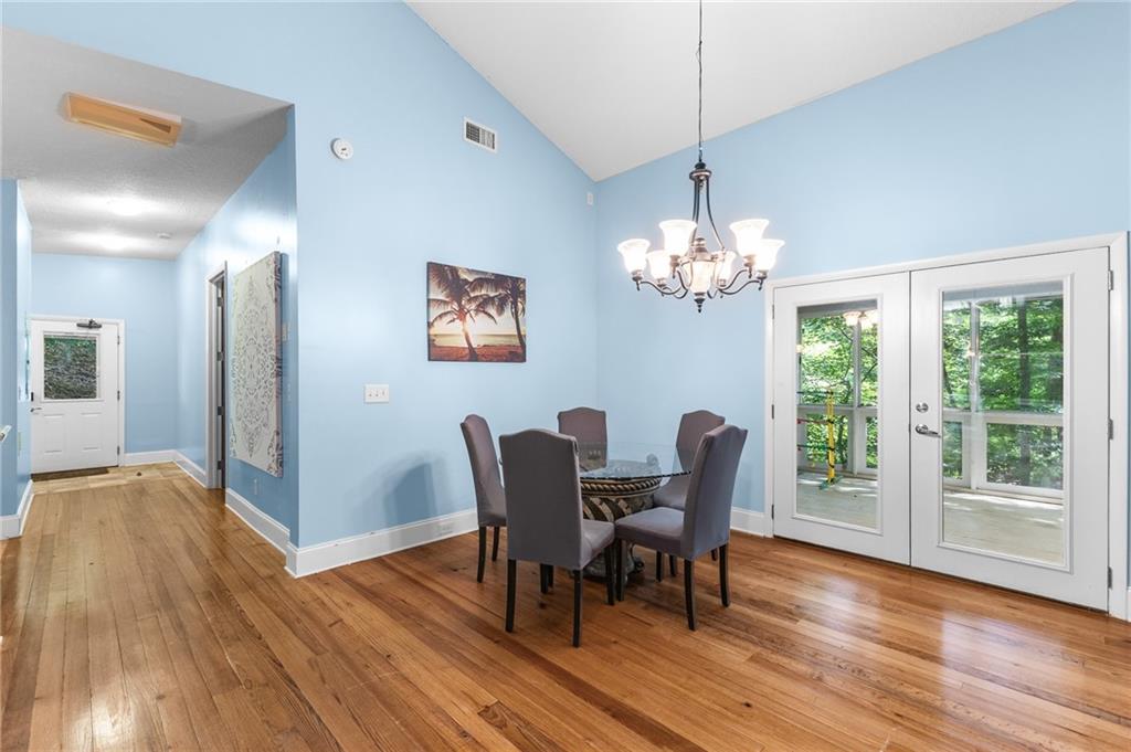 6567 Tahiti Way Flowery Branch, GA 30542 - Photo 11 of 36 a dining room with furniture a large window and wooden floor