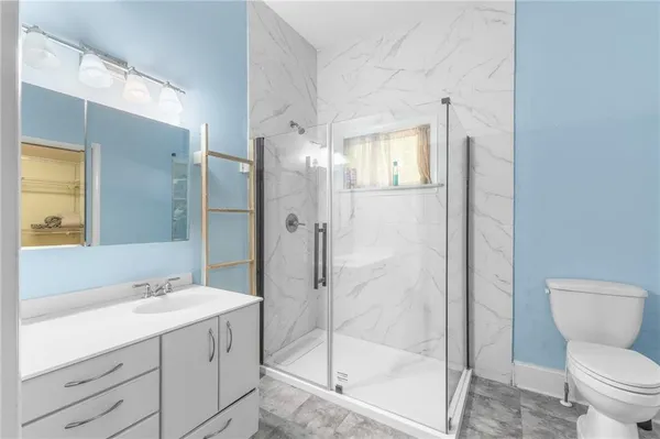 a bathroom with a shower sink mirror and toilet