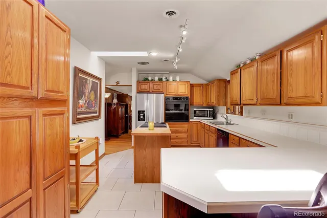 a large kitchen with stainless steel appliances kitchen island granite countertop a refrigerator and a stove top oven